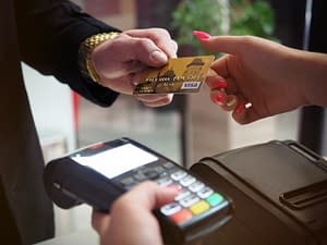 Buyer handing credit card to seller using card machine